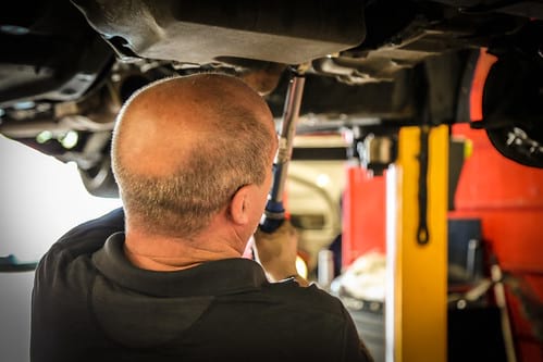 Mechanic working on underside of car in auto repair shop